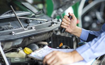 Person working on the engine of a car with the hood up. West Financial Services.