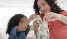 Mother teaching daughter to save using a jar. West Financial Services