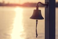 A bell on a post near the water. West Financial Services, Inc. 