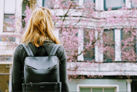 Young woman with a backpack in front of a college building. West Financial Services.