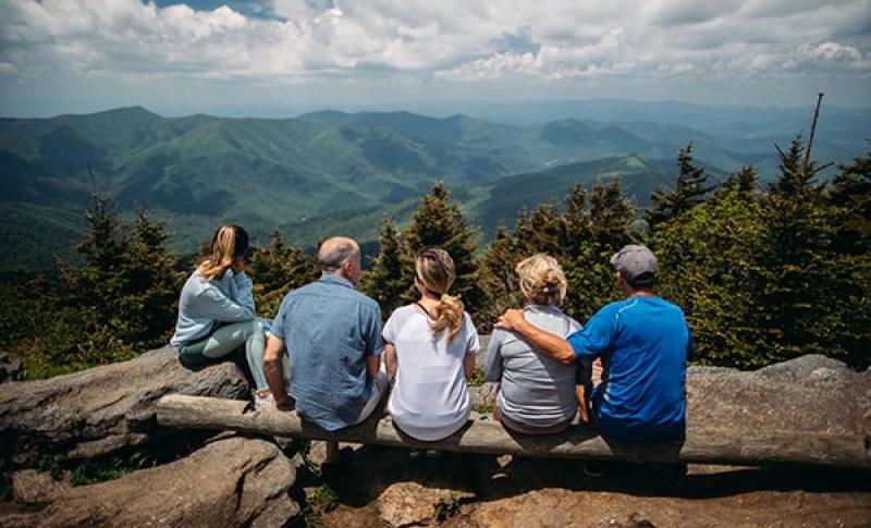 Family sitting on a mountain looking at other mountains. West Financial Services, Inc.